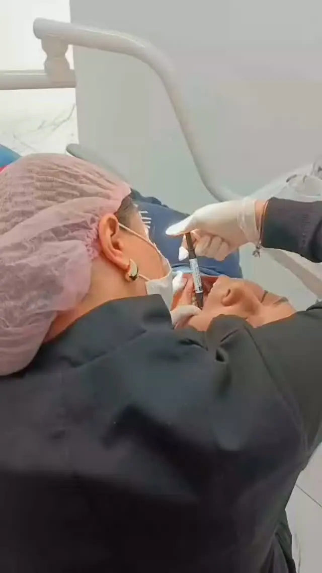 Dra. Eduarda Souza com touca e máscara, realizando restauração em paciente na Sorria Feital